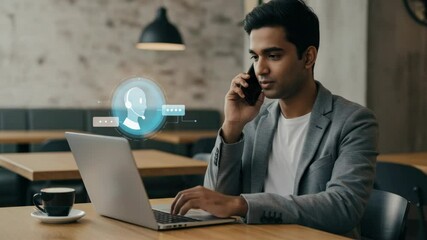 A person sits at a cafe table, working on a laptop and talking on a phone. A holographic contact icon overlays the laptop - Powered by Adobe