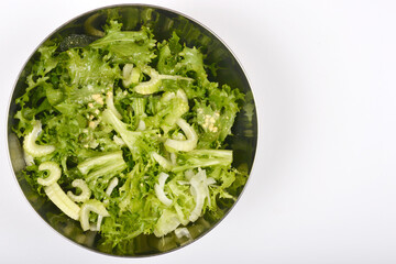 This top-down shot presents a vibrant green salad in a stainless steel bowl, featuring crisp lettuce and sliced celery against a plain white background