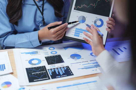 Businesswomen analyzing financial charts and graphs, discussing company performance and investment strategies