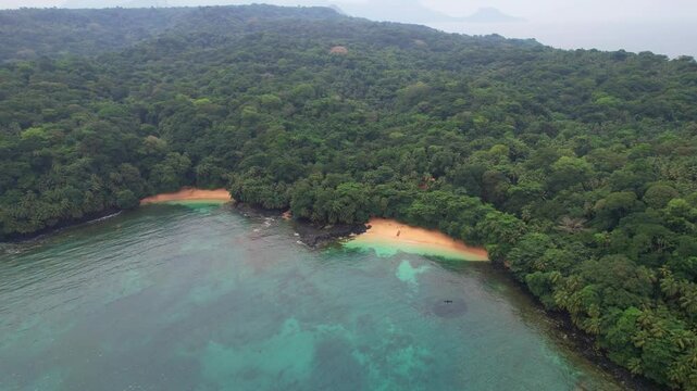 Flying in a circle and rising over the sea with a view of Margarida beach and the island's green forest in the background. Ilha do Principe (Prince Island) Africa