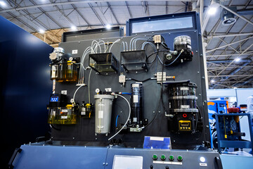 Detail of industrial lubrication equipment showing translucent oil containers, gauges, and pipes on a dark panel. Maintenance and automation theme.