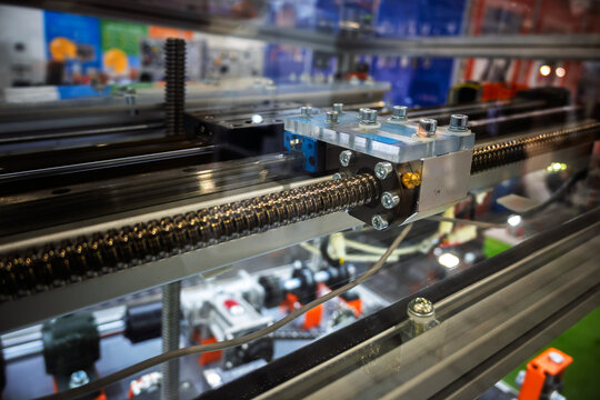 Close-up detail of a ball screw mechanism and linear guide rail on industrial automation machinery. Precision engineering components for linear motion systems.
