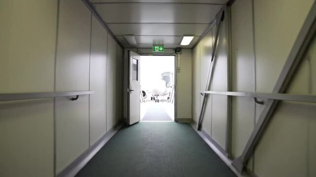 View from inside an airport jet bridge towards an awaiting airplane.