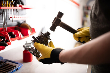Serviceman Repairing Auto Part With Hummer At Workbench