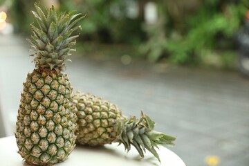 Fresh ripe pineapples on white table outdoors, closeup. Space for text
