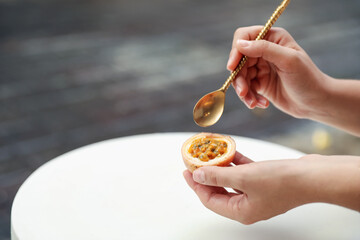 Woman eating passion fruit at table outdoors, closeup. Space for text