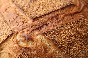 Tasty fresh bread with sesame seeds as background, closeup