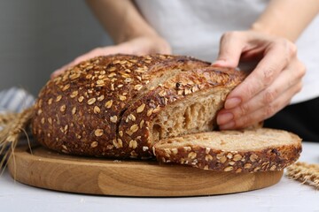 Woman with freshly baked bread at light table against grey background, closeup