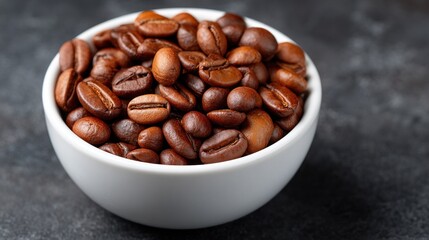 Fototapeta premium Roasted coffee beans in a white bowl on dark surface Close up view of aromatic coffee beans