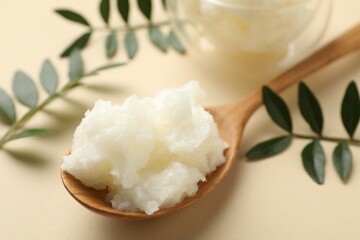Shea butter and leaves on beige background, closeup