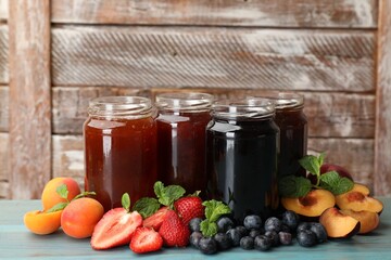 Different jams in jars and ingredients on blue wooden table. Space for text