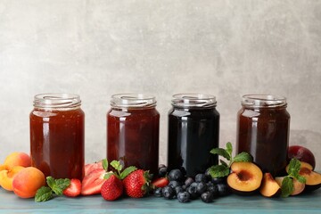 Different jams in jars and ingredients on blue wooden table. Space for text