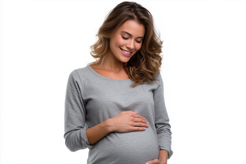 Smiling pregnant woman gently touching her belly while standing against a white background