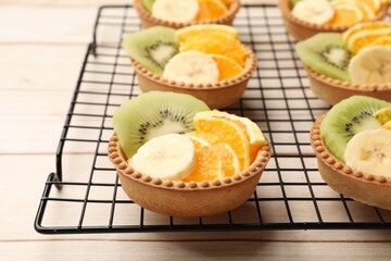 Tartlets with fruits on wooden table, closeup. Delicious dessert