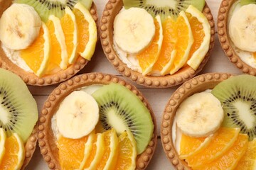 Tartlets with fruits on table, top view. Delicious dessert
