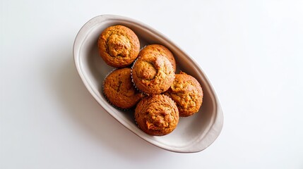 Top view of rustic round ceramic dish with freshly baked carrot muffins in parchment paper on empty white surface, sharp focus, simple captivating composition for stock photo.