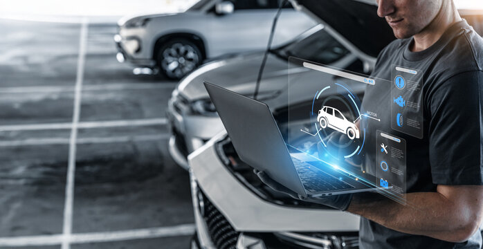 Mechanic using laptop checking up on car engines parts for fixing and repair.