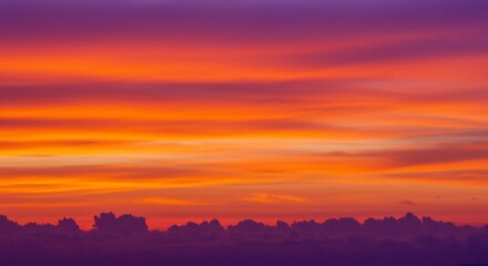 Obraz premium Fiery Sunset Hues Over Silhouetted Cloudscape