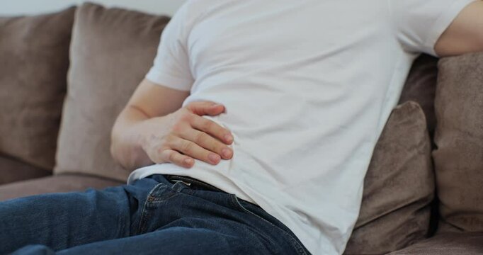 Close up of man feeling abdominal, ulcer in his tummy at home. Unrecognizable man feels bad digestive problems abdominal pain. People health care problem.