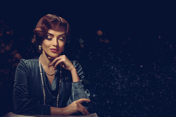 Portrait of charming young woman with vintage evening makeup and hairstyle. Woman with pearl necklace and retro hairstyle in thoughtful pose