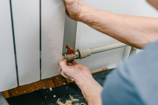 Plumber installing new central heating radiator at home. Unboxing a modern heating battery for home installation, preparation for cold weather season