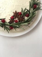 Deliciously decorated cake with fresh rosemary, star anise, and red berries for a festive celebration