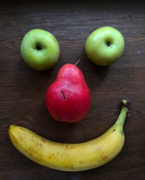 Naklejki green apples, red pear and bananas on dark wooden background 