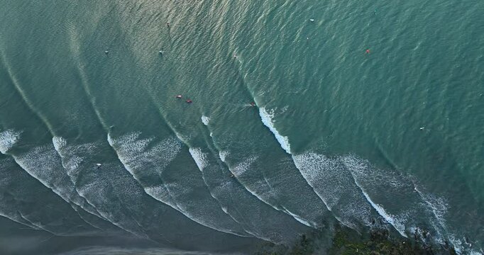 Turquoise waves form parallel lines and break near the shore in Jericoacoara, Brazil. Slow motion a top-down drone aerial