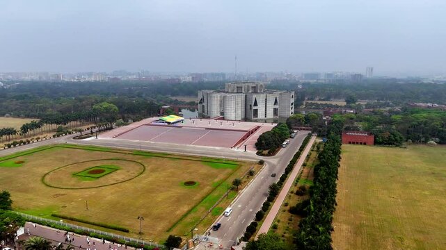 Cinematic pan aerial drone shot of the Jatiya Sangsad Bhaban parliament building and it's main plaza.