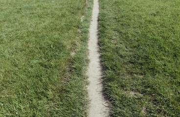 Narrow path on a green meadow with freshly cut grass, concept of direction, choice, and journey through peaceful natural countryside landscape