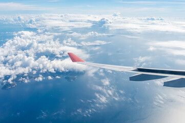 Fototapeta premium The wing of an airplane on the background of clouds in flight. Hong Kong Islands from below