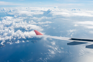 The wing of an airplane on the background of clouds in flight. Hong Kong Islands from below