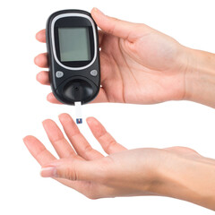 A person holds a blood glucose meter with a test strip near their fingertip for monitoring blood sugar levels.
