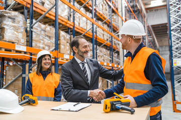 Manager shaking hands with a worker in a logistics warehouse, finalizing a successful business deal
