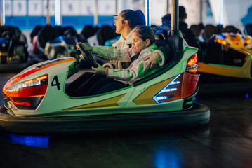 Mother and daughter enjoying bumper cars at amusement park