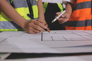 Closeup of team of industrial engineers meeting analyze machinery blueprints consult project on table in manufacturing factory. Working in manufacturing plant or production plant.