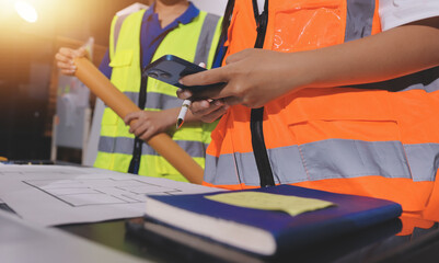 Closeup of team of industrial engineers meeting analyze machinery blueprints consult project on table in manufacturing factory. Working in manufacturing plant or production plant.