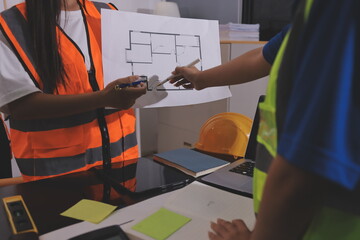 Closeup of team of industrial engineers meeting analyze machinery blueprints consult project on table in manufacturing factory. Working in manufacturing plant or production plant.