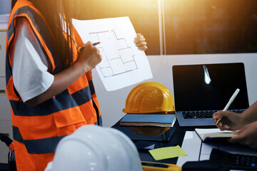 Closeup of team of industrial engineers meeting analyze machinery blueprints consult project on table in manufacturing factory. Working in manufacturing plant or production plant.