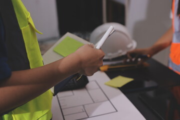 Closeup of team of industrial engineers meeting analyze machinery blueprints consult project on table in manufacturing factory. Working in manufacturing plant or production plant.