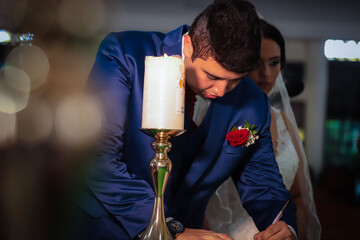 Groom signing the wedding registry while candlelight creates a romantic atmosphere during an intimate ceremony