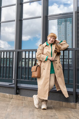 Happy elderly Caucasian business woman of 60 years old walks along the city streets and smiling. Urban style. Concept of beautiful old age and active longevity.