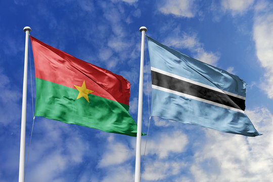 A Burkina Faso and Botswana flag, a metaphor for Southern African unity, wave together against a blue sky, symbolizing friendship and cultural exchange. - Powered by Adobe