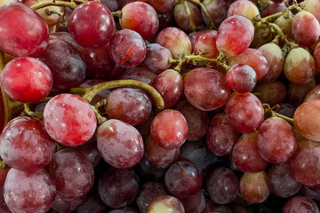 Close-up of fresh red grapes with a natural bloom on the skin, arranged in a tight cluster. The image highlights texture, freshness, and vibrant color, ideal for food concepts.