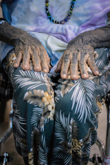 Close-up of elderly woman's tattooed hands resting on her lap, showcasing traditional body art and aging gracefully. Cultural heritage and wisdom through the hands of time.

