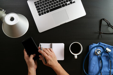 Doctor Using Smartphone with Medical Supplies and Notebook on Desk