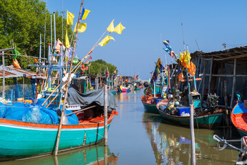 Colorful traditional fishing boats docked along canal in coastal fisherman village, Thailand