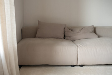 Modern sofa adorned with plush pillows, filling a bright living room with elegant curtains, perfect for enjoying cozy, relaxing moments