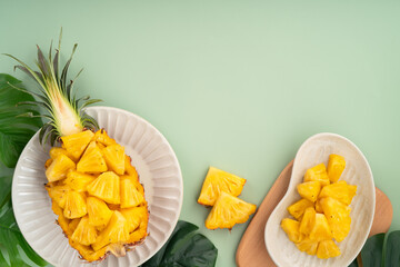 Fresh pineapple chunks served in a pineapple bowl on green table background.