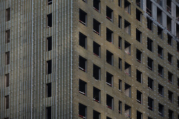 Close up of insulating panels being installed on a high rise building during construction, showcasing the process of enhancing energy efficiency
